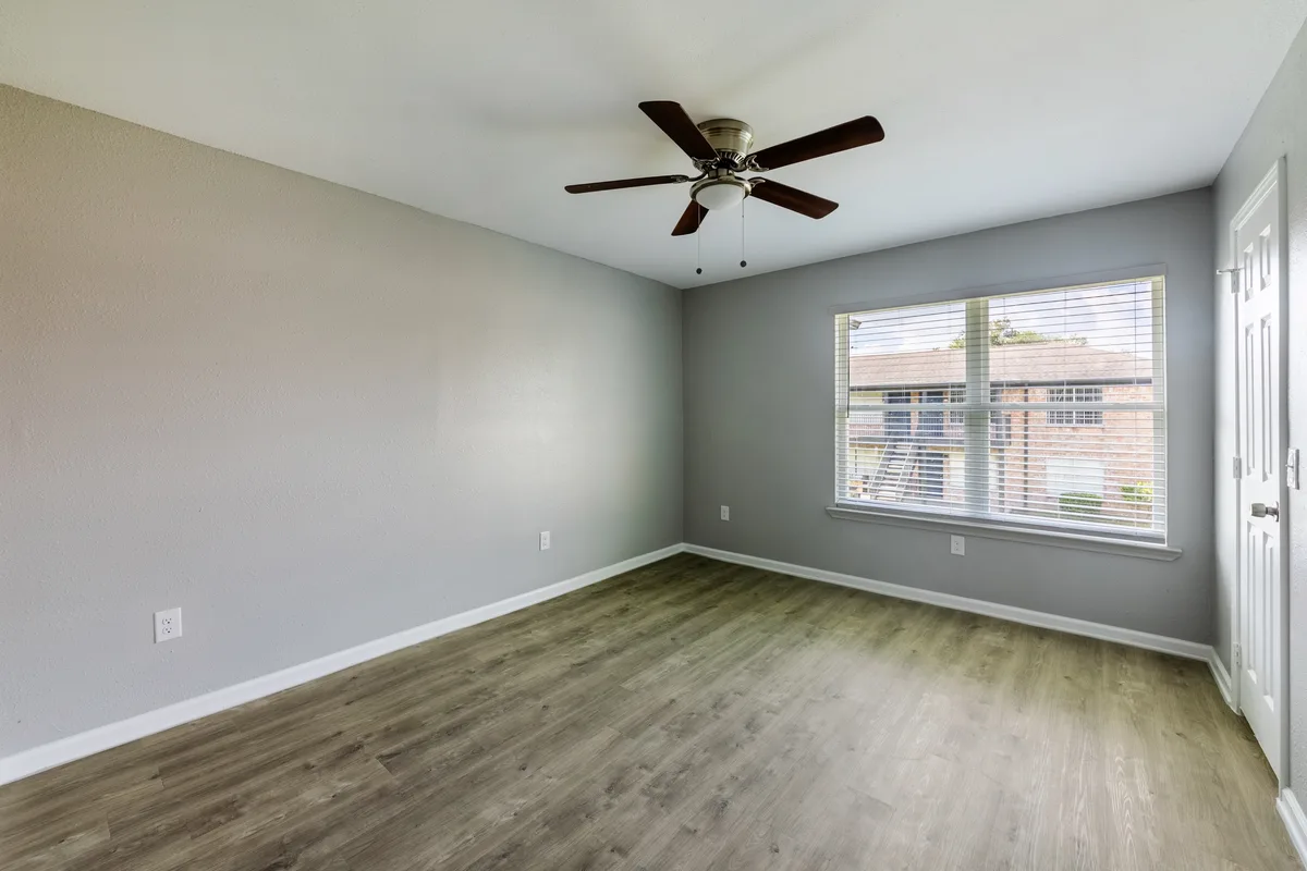 Bedroom with wood-look flooring, gray accent walls, and a large window