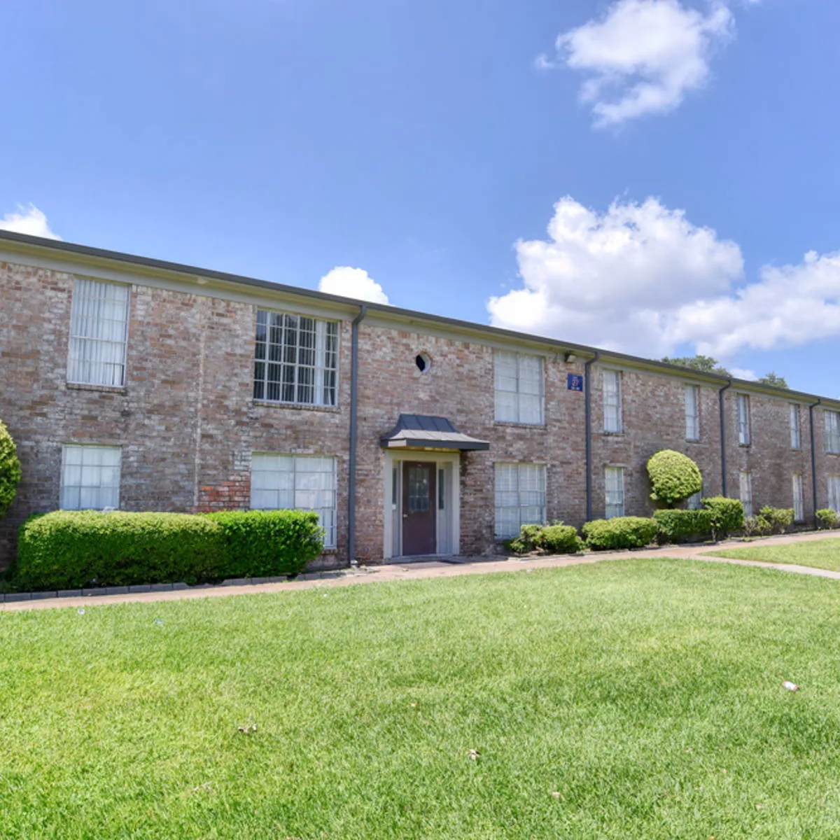 Painted-brick two-story building with a gabled entry canopy and expansive front lawn