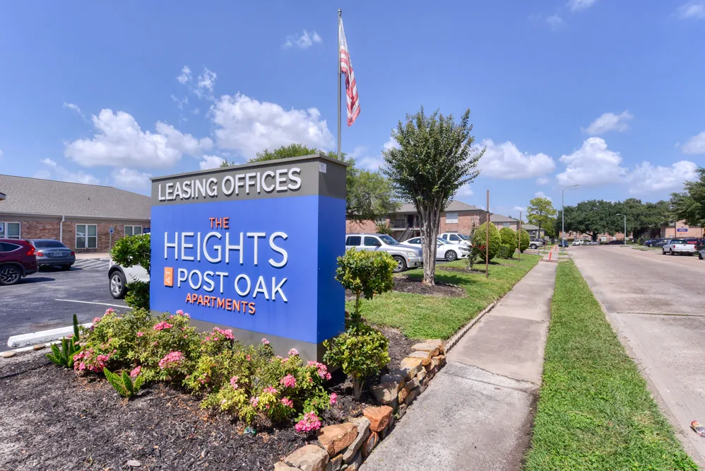 The Heights Post Oak monument sign and leasing office entrance framed by flowering landscaping