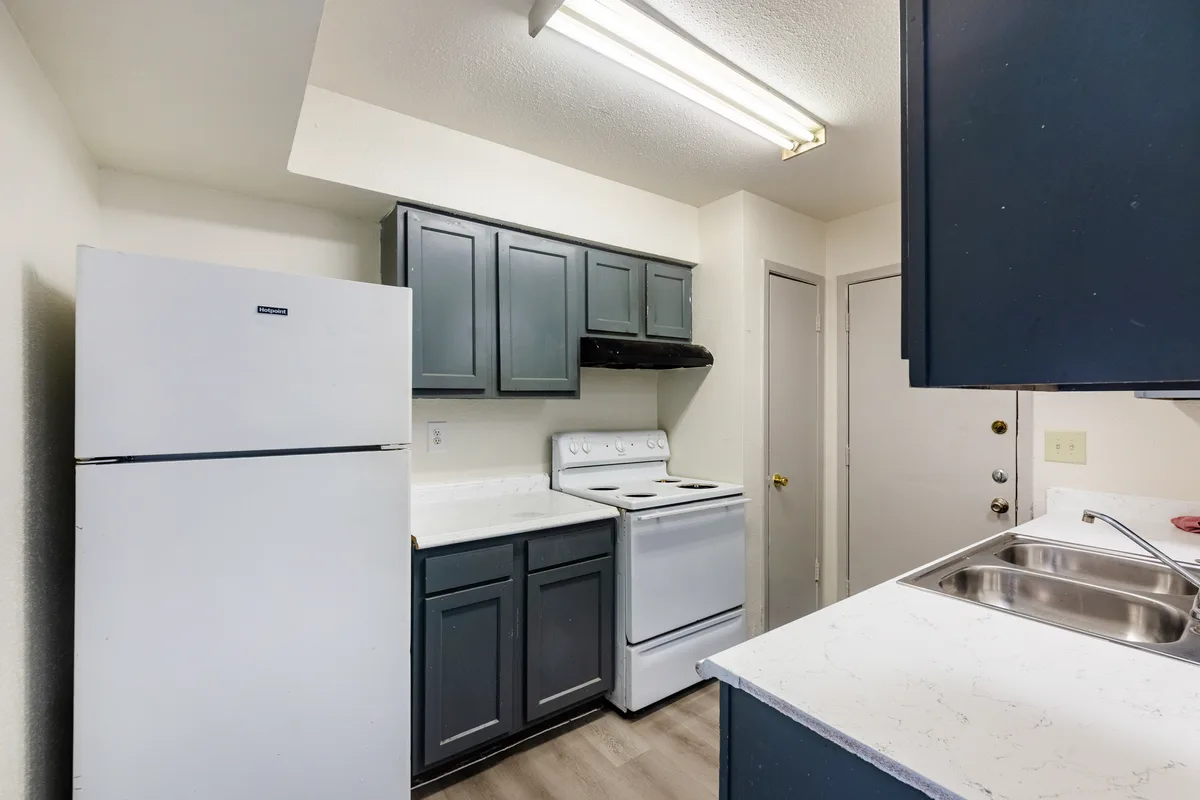 Galley kitchen with gray cabinets, white appliances, and a stainless double sink