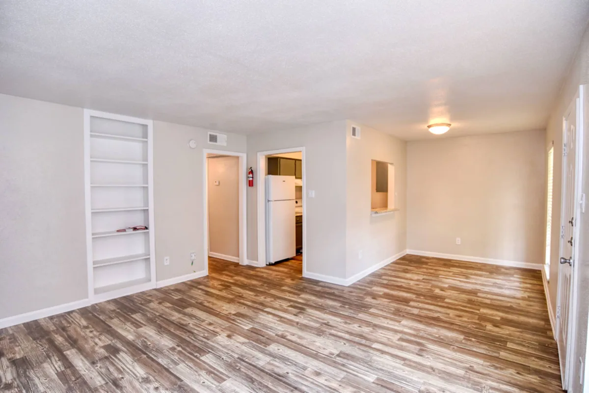 Open living space with white built-in shelving and a pass-through to the kitchen
