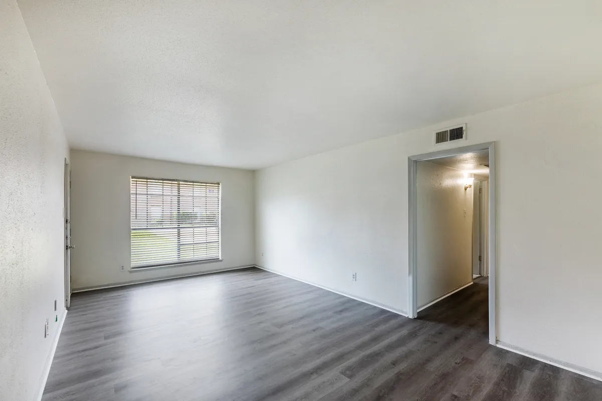 Bright living room with a picture window, wood-look flooring, and hallway access