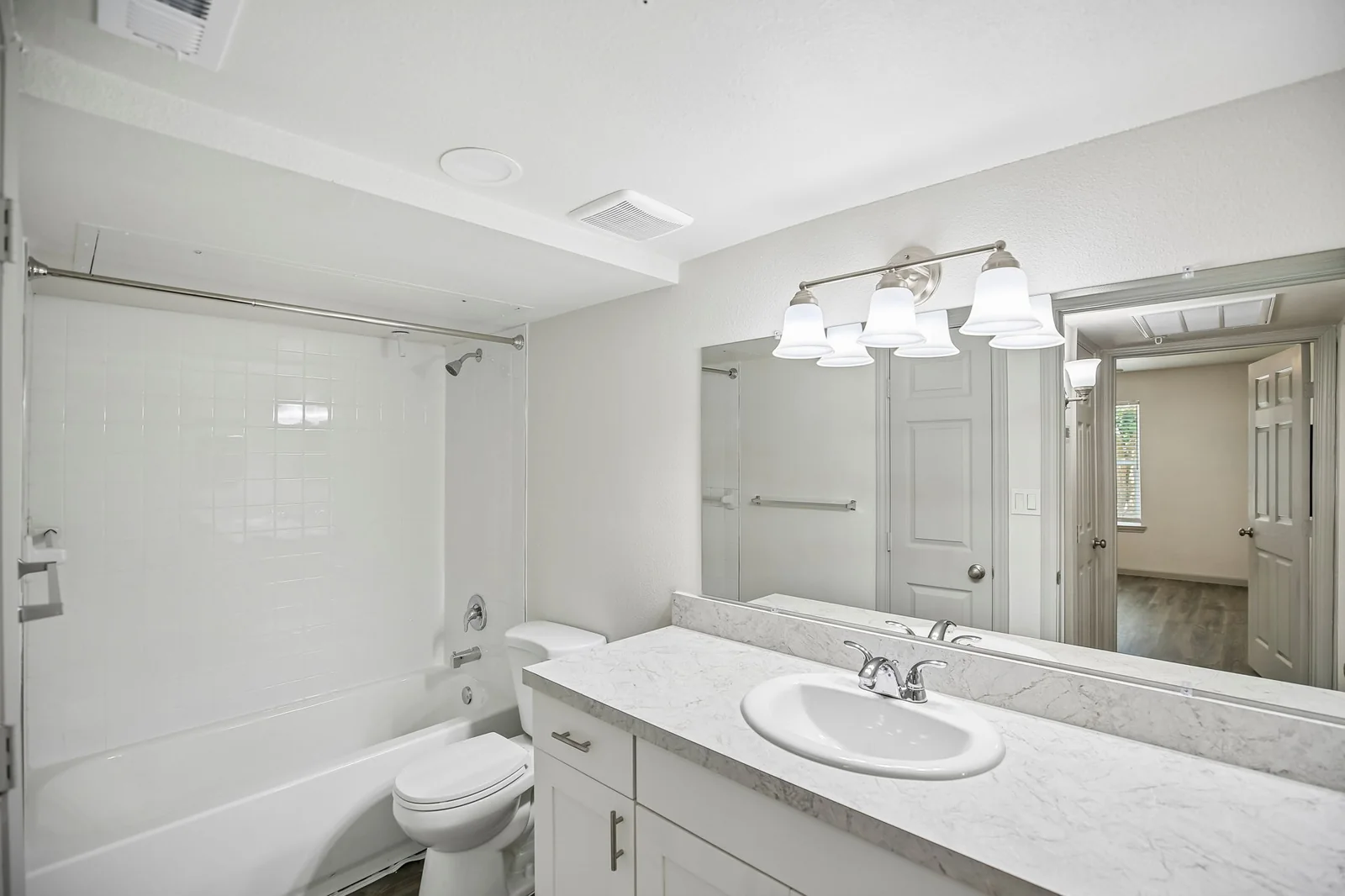 Renovated bathroom with a wide vanity mirror and tub-shower