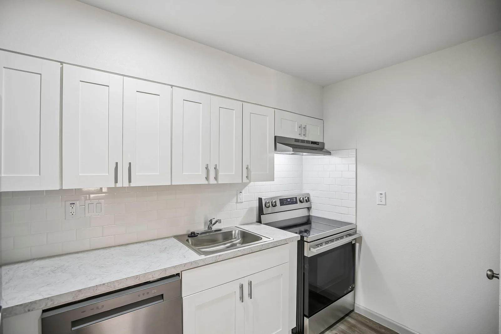 Renovated one-bedroom kitchen with white shaker cabinets, stainless appliances, and tile backsplash
