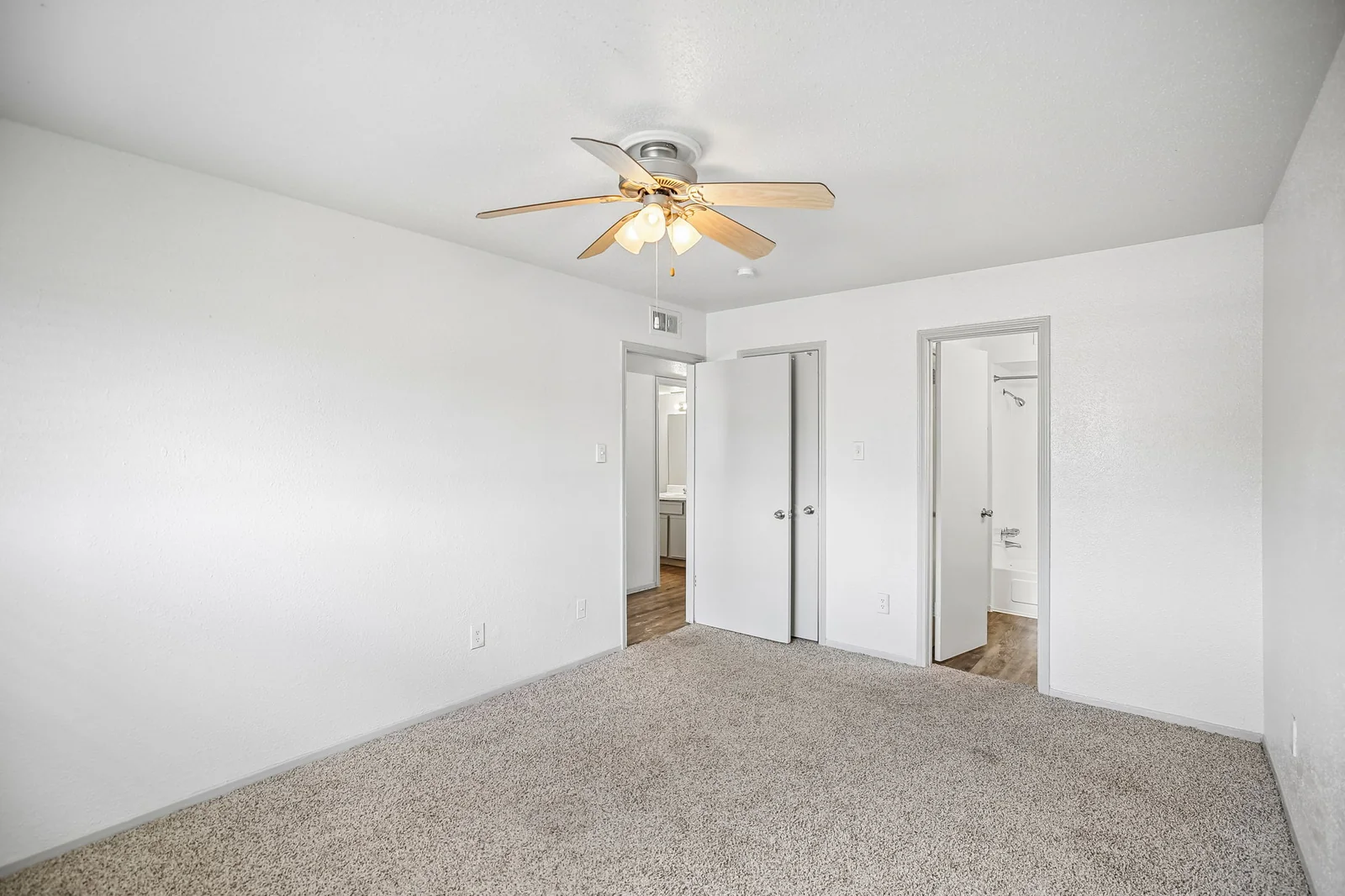 Carpeted two-bedroom bedroom with a ceiling fan and closet wall
