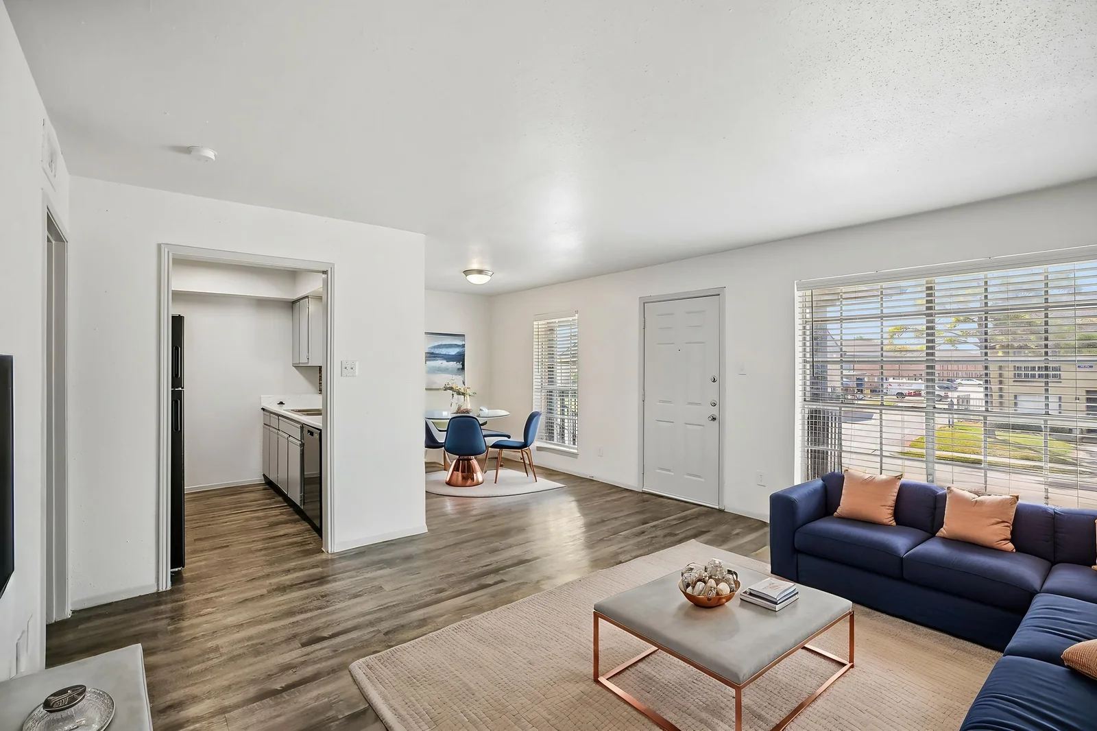 Virtually staged two-bedroom living room with a navy sofa, open to the kitchen