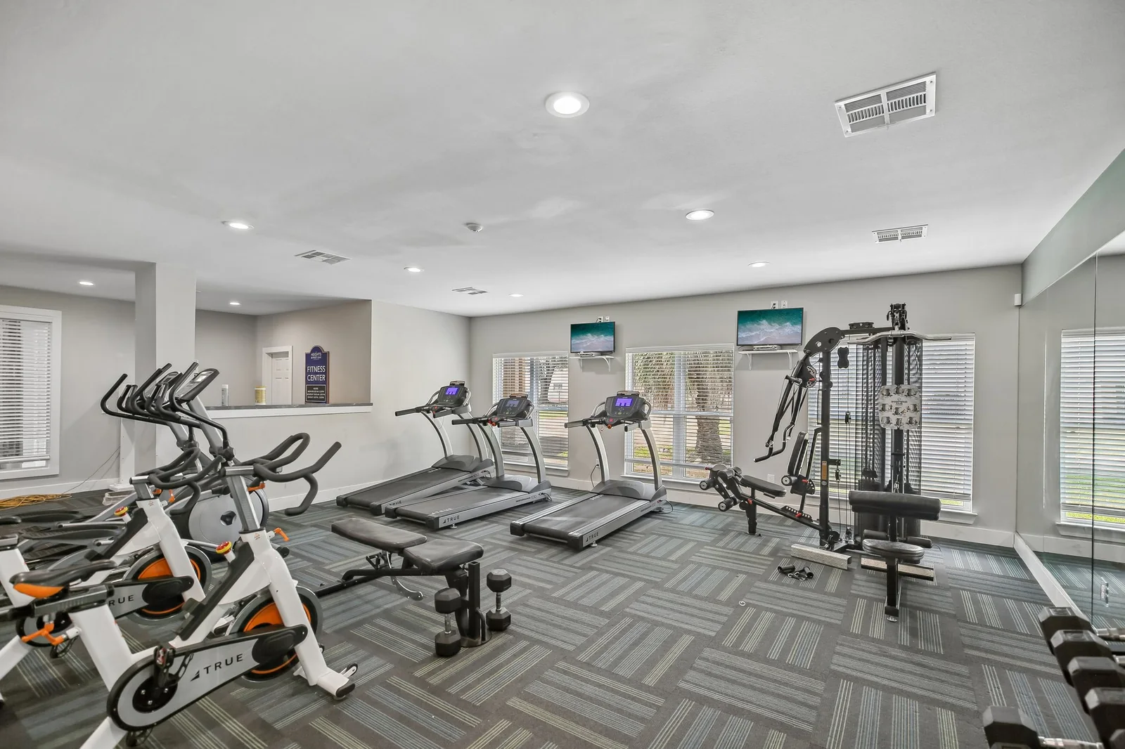 Renovated fitness center with cardio machines, spin bikes, and free weights
