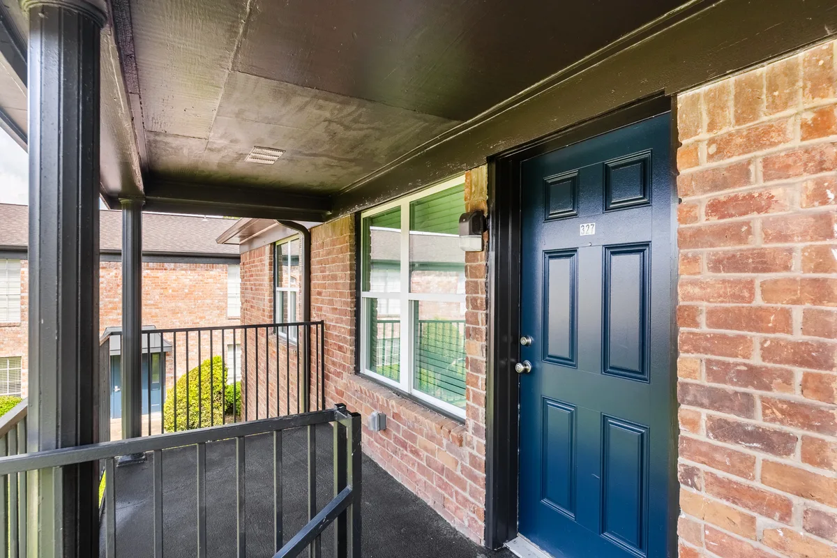 Covered second-floor walkway leading to a navy unit entry door set in brick