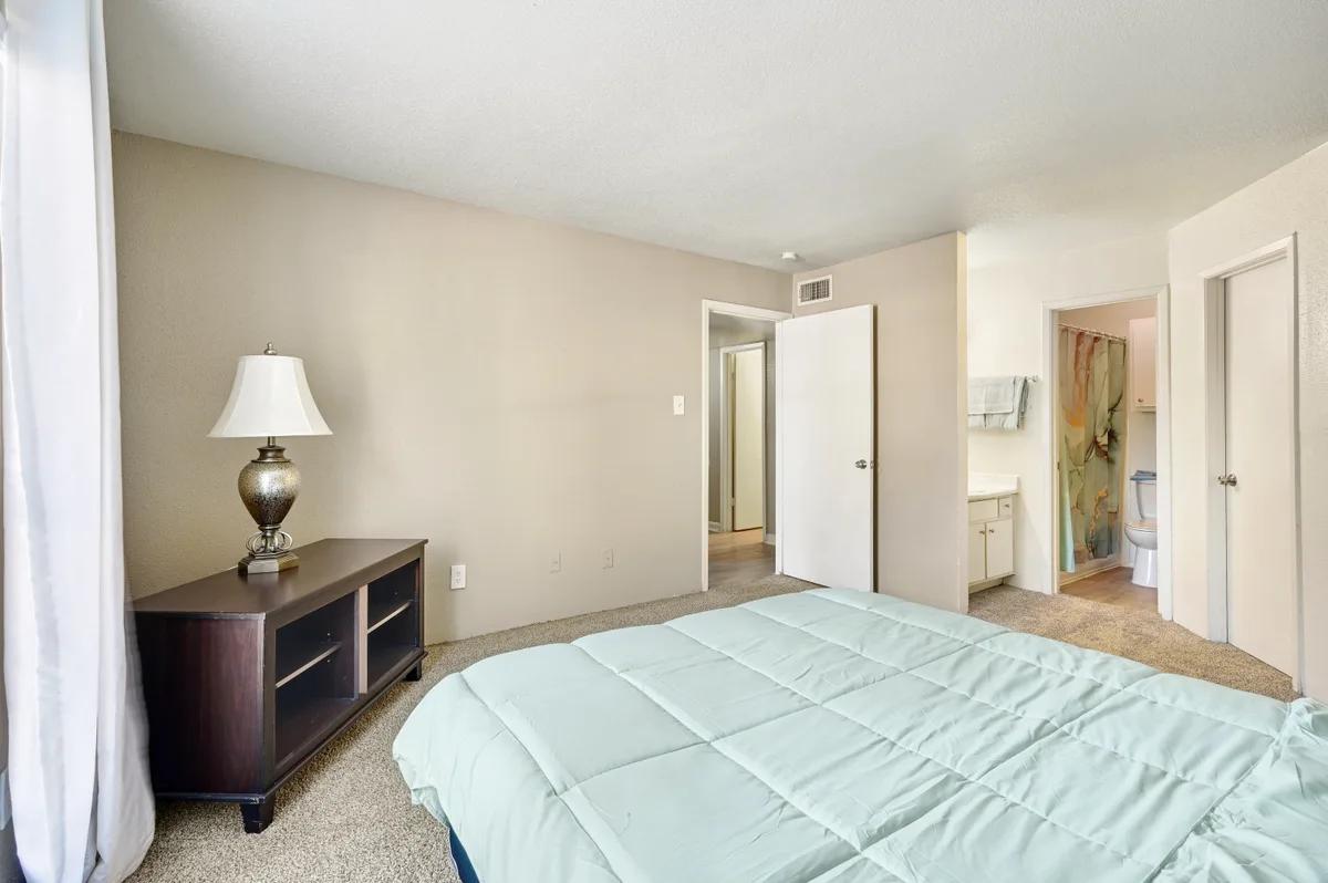 Spacious carpeted bedroom with a dresser and en-suite bathroom access