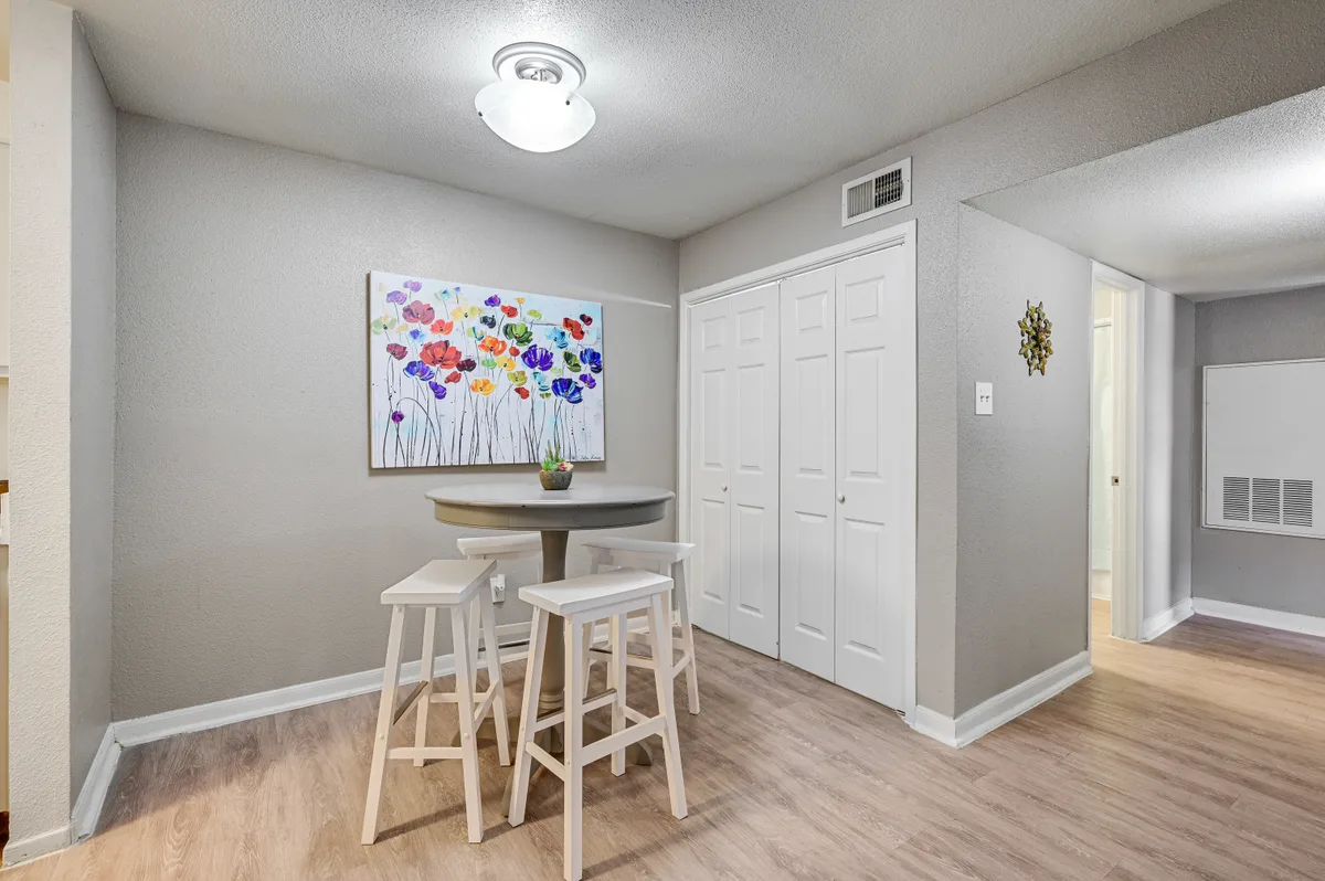 Dining nook with a bistro table, stools, and double-door closet on wood-look flooring