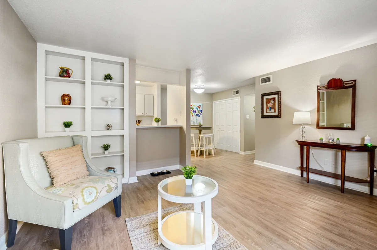 Open living area with built-in shelving, wood-look floors, and a view to the kitchen