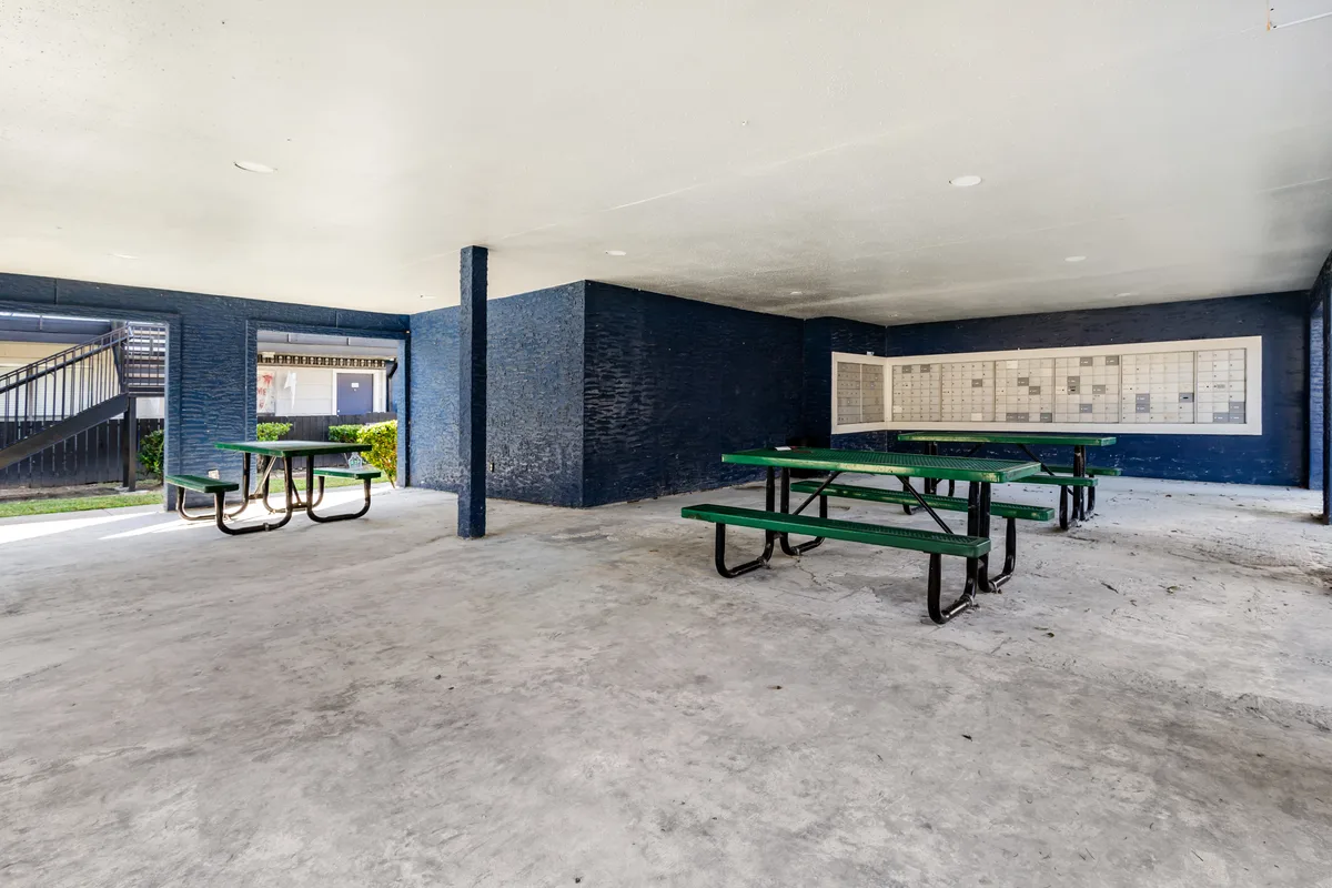 Covered picnic area with green tables beside a resident mailbox kiosk