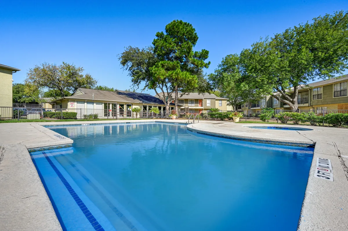 Swimming pool with an expansive sundeck framed by mature shade trees