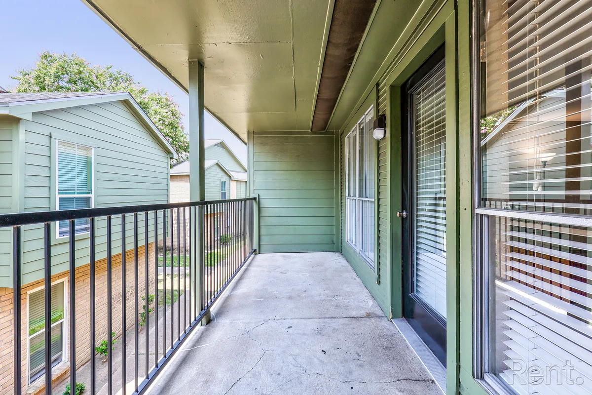 Second-floor covered balcony with metal railing overlooking the grounds