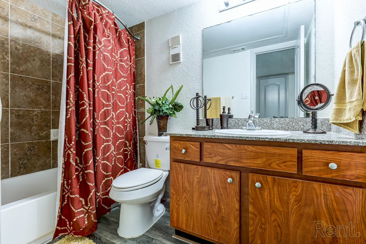 Bathroom with tiled shower-tub, granite-topped wood vanity, and framed mirror