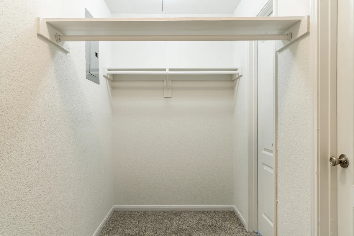 Walk-in closet with a full-length hanging rod and overhead shelf