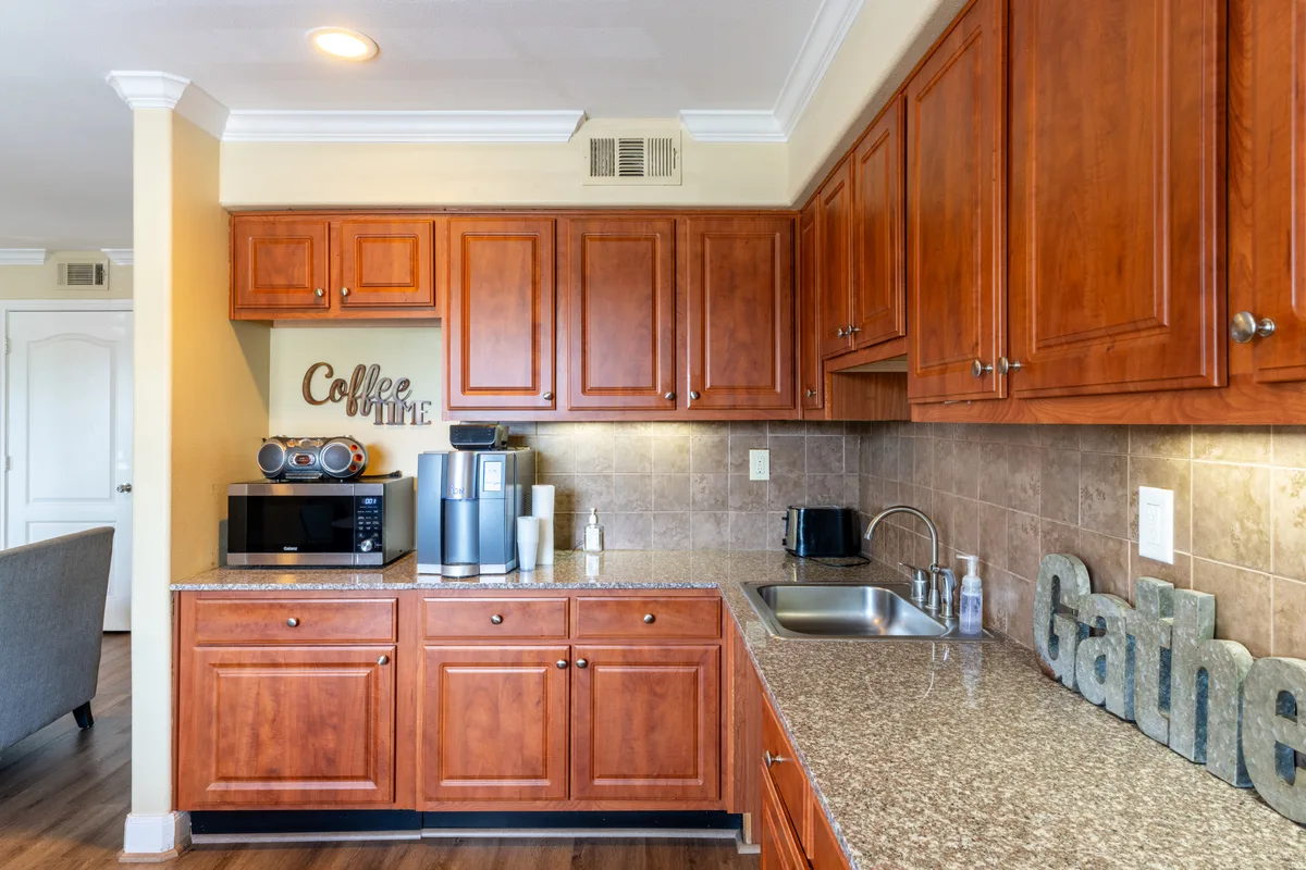 Clubhouse coffee bar with granite counter, stainless microwave, and cherry cabinetry