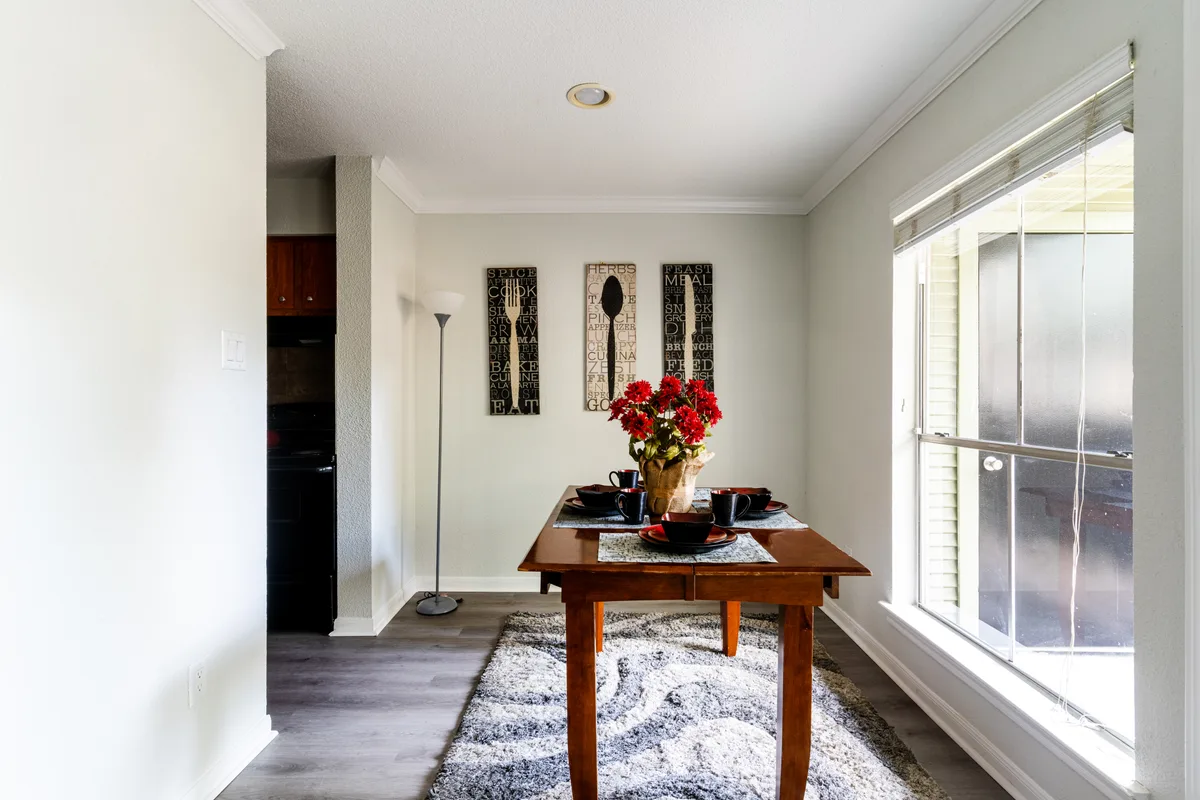 Dining area with a wood table beneath a bright window and crown molding