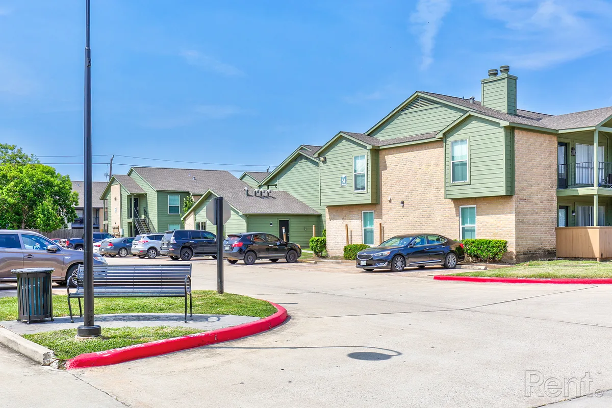 Green-and-brick two-story residential buildings lining a repainted parking lot