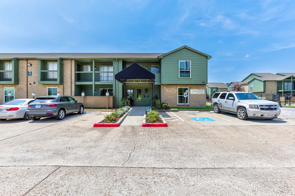 Two-story leasing center with green siding, brick facade, and canopied entrance