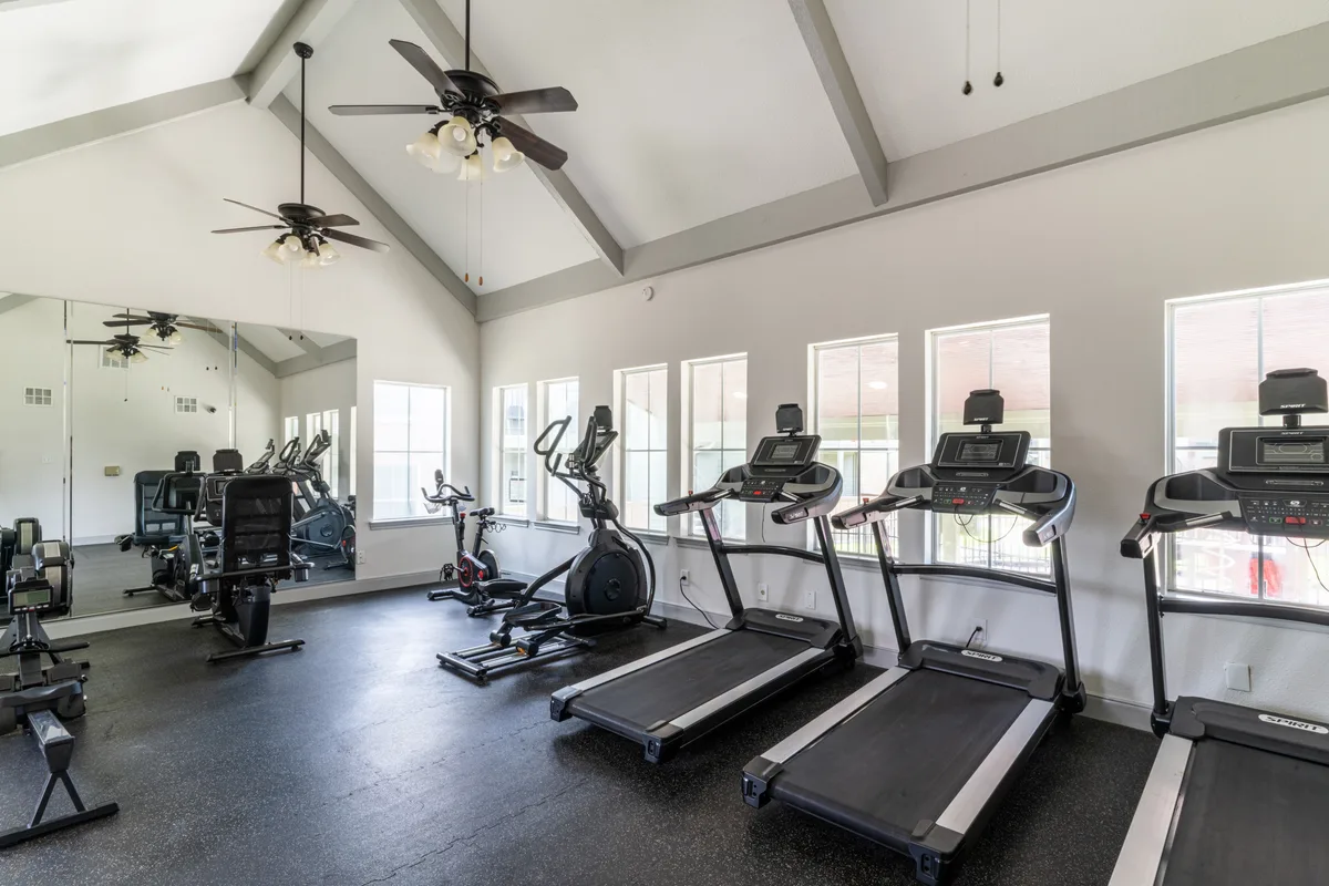 Fitness center with treadmills, an elliptical, and a mirrored wall under vaulted ceilings
