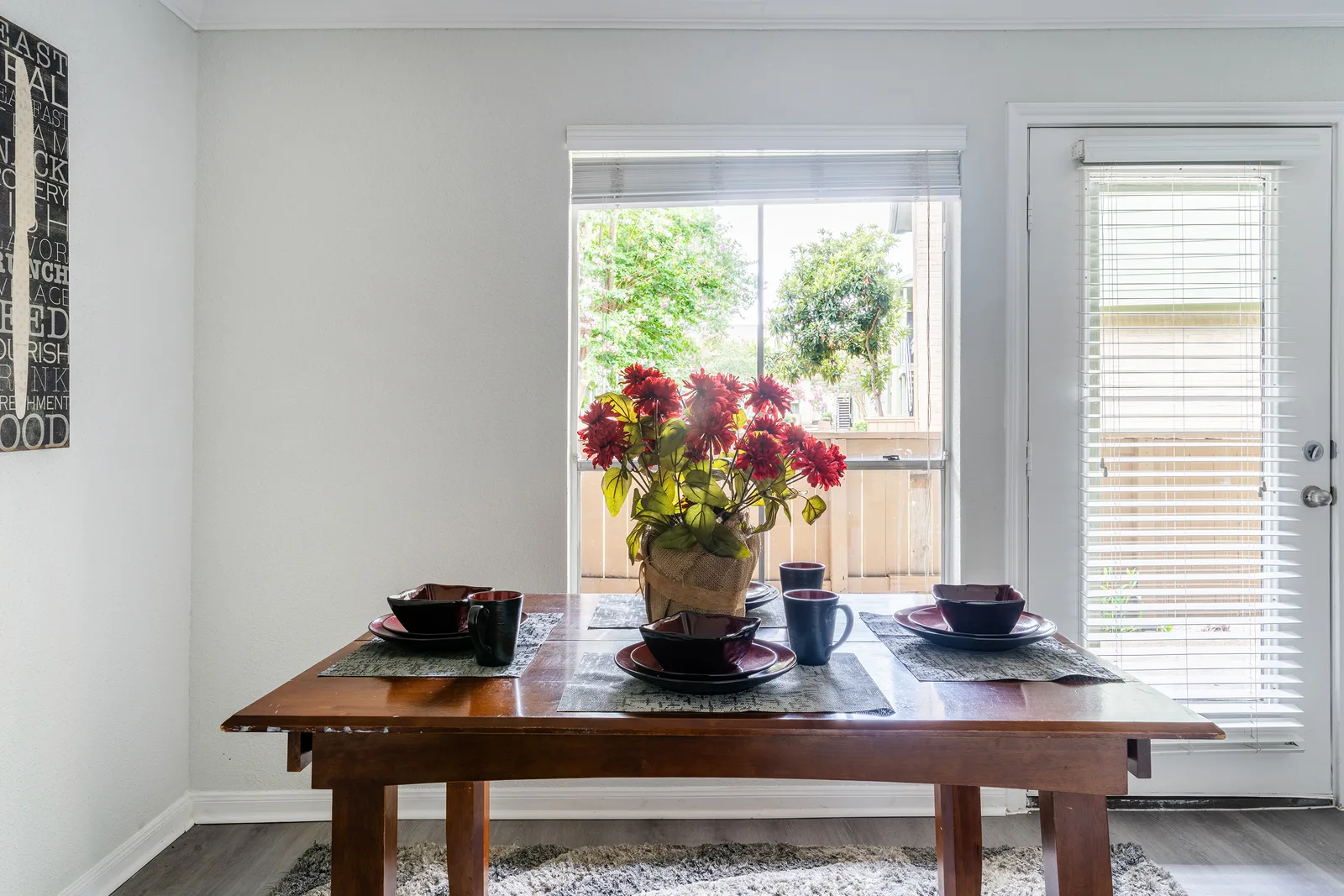Wood dining table set for four in front of a window and glass patio door
