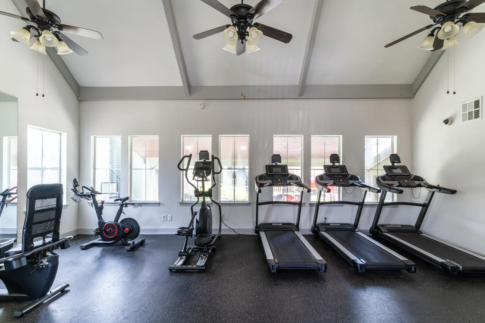 Fitness center with treadmills, an elliptical, and a recumbent bike under a vaulted ceiling