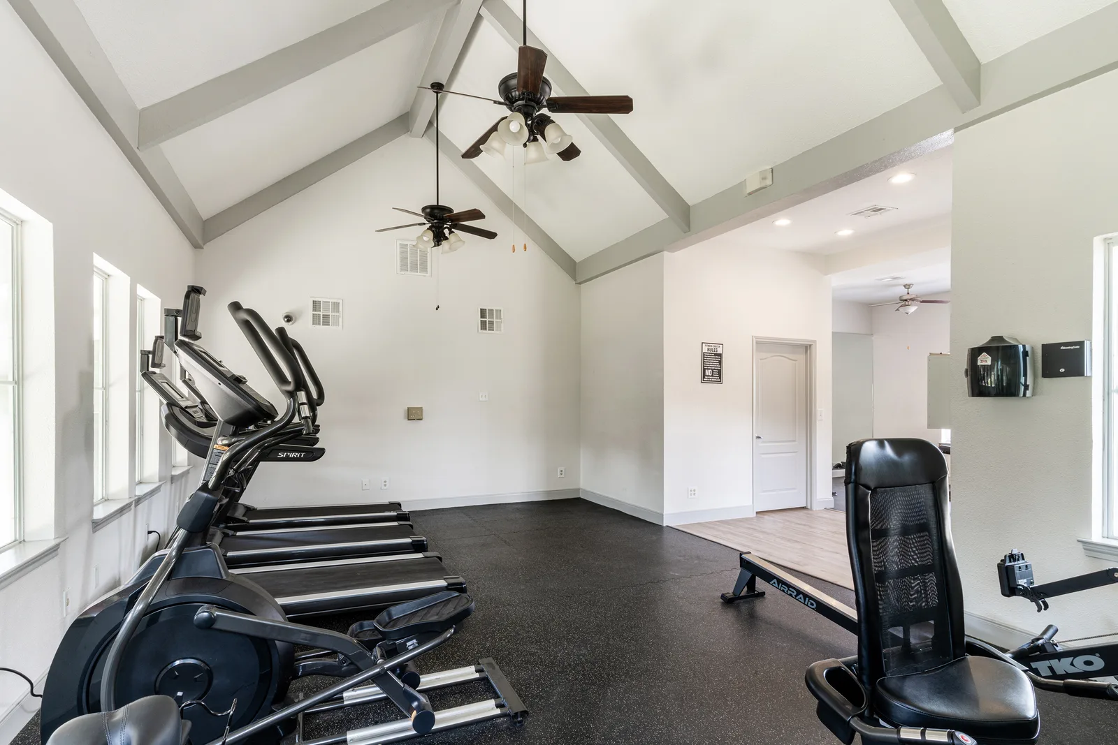 Fitness room with ellipticals and a rowing machine under a vaulted ceiling