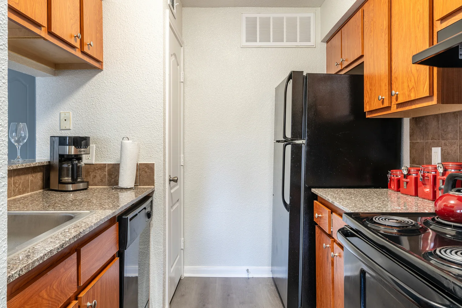 Kitchen with granite counters, oak cabinets, black appliances, and a coffee maker
