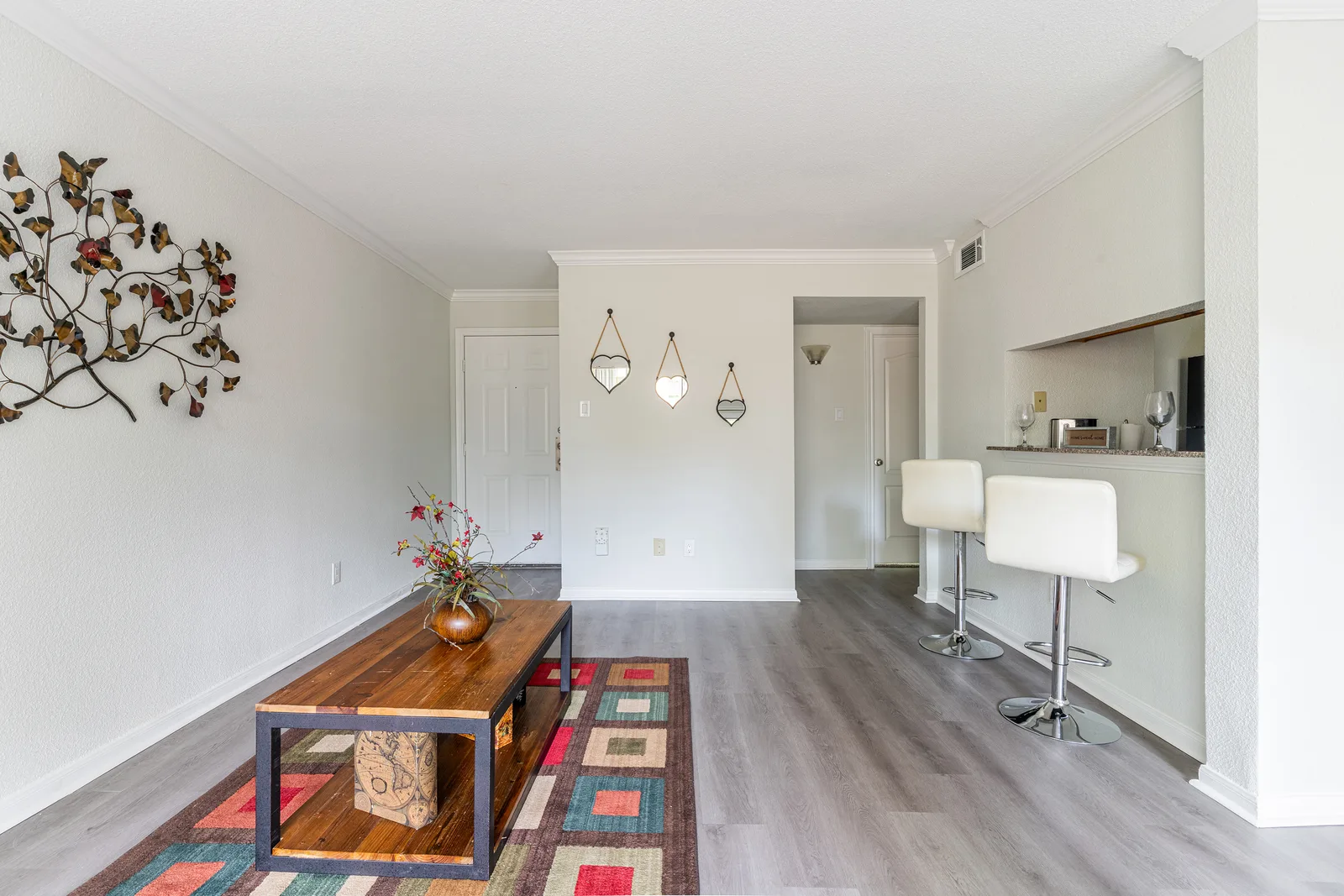 Open living room with a wood-top coffee table, breakfast bar stools, and wood-look flooring