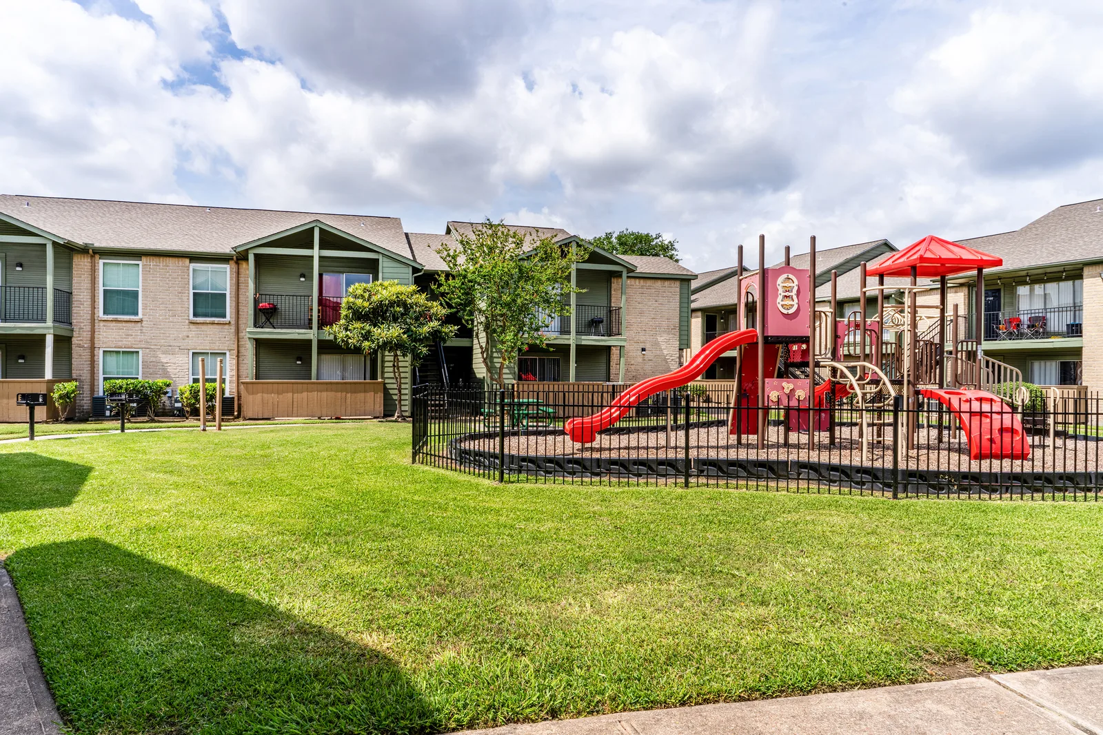 Fenced children's playground with a red slide beside the residential buildings
