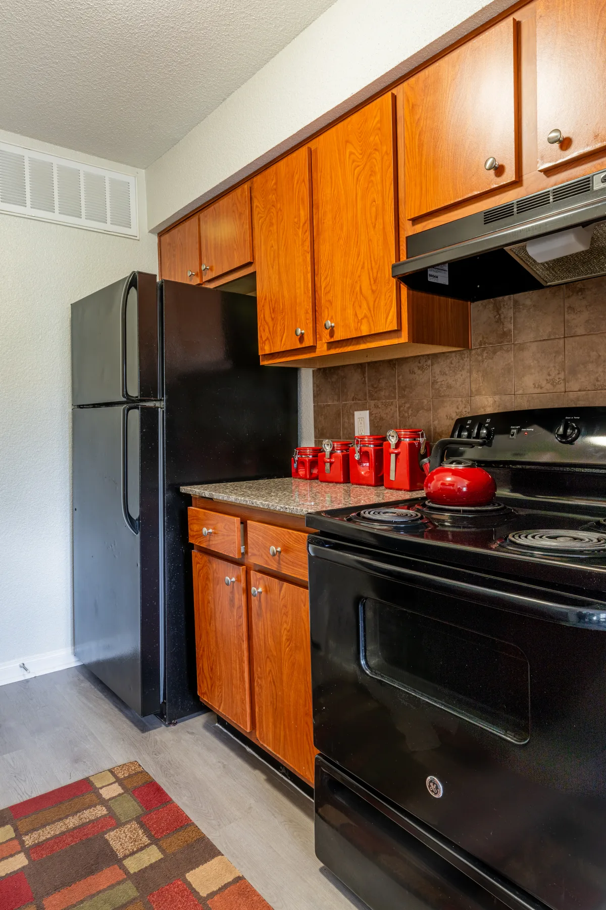 Kitchen with cherry cabinets, granite-look counters, and black GE appliances