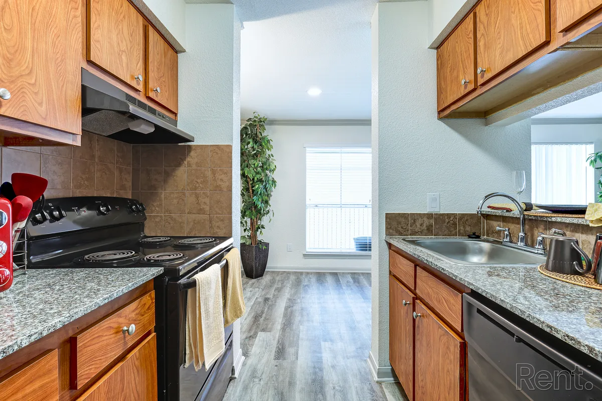 Galley kitchen with granite counters, a black range, and stainless dishwasher