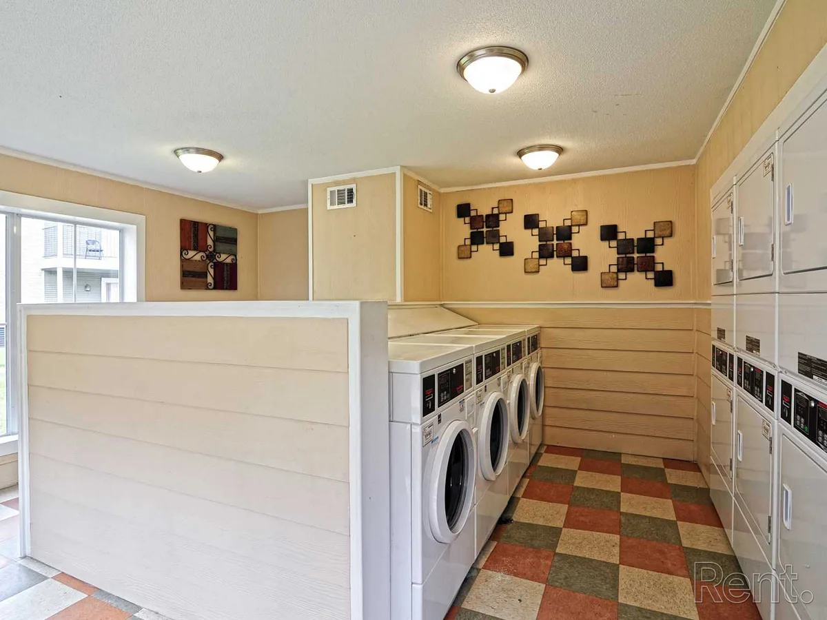 Community laundry room with front-load washers, stacked dryers, and tile flooring