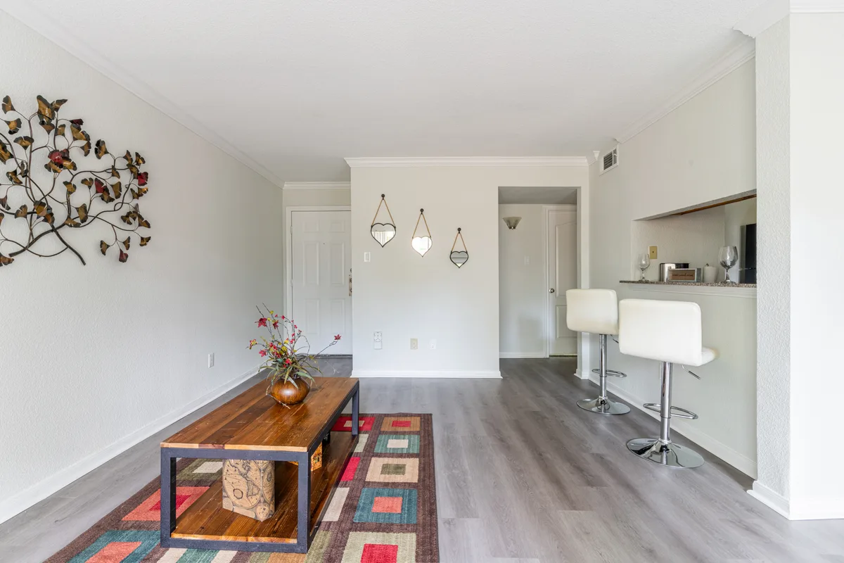 Open living and dining area with breakfast bar seating and wood-look floors