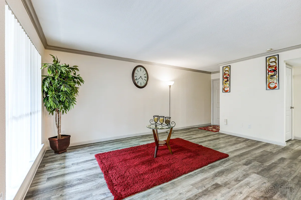 Spacious living room with wood-look flooring, crown molding, and bright windows