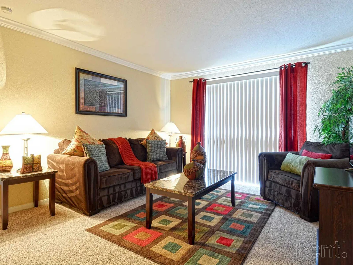 Carpeted living room staged with sofas and a sunlit patio-door view