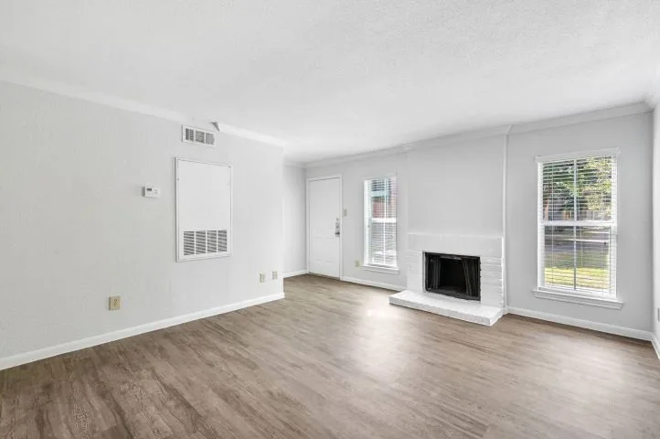 Living room with a white-brick fireplace, wood-plank flooring, and large windows