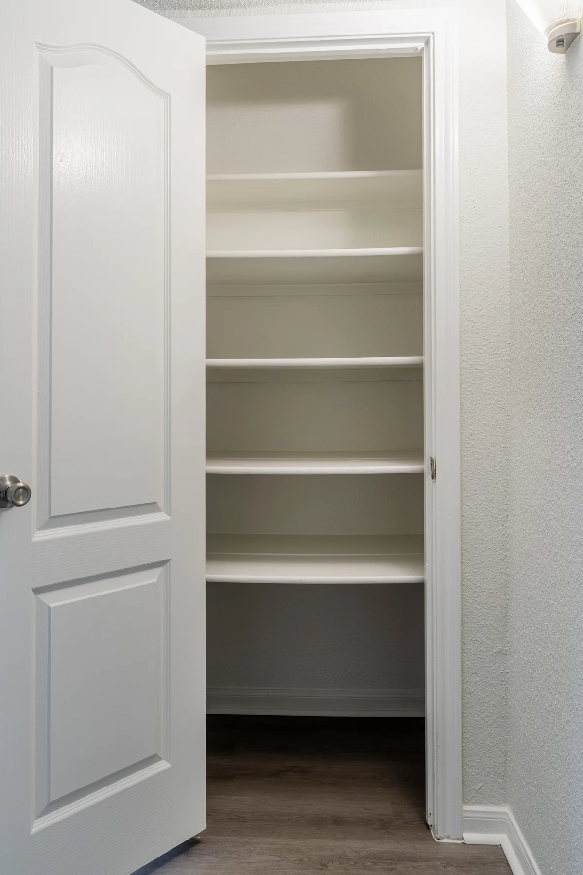Deep linen pantry closet with five white built-in shelves