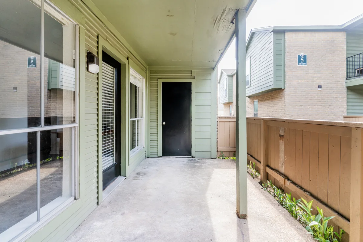 Ground-floor covered patio with privacy fencing and an exterior storage door