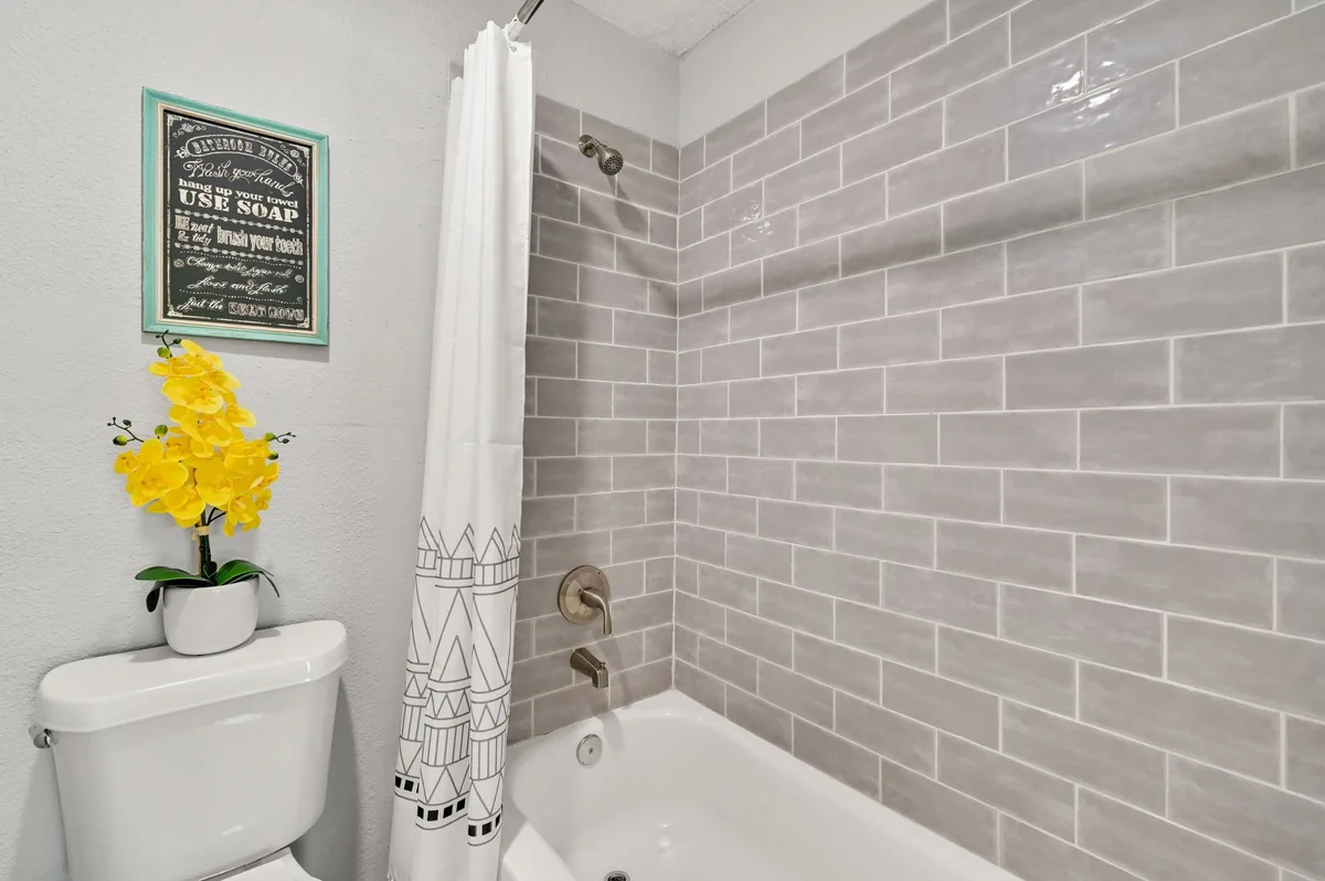 Bathroom with a gray subway-tile tub surround, brushed-nickel fixtures, and a shower curtain