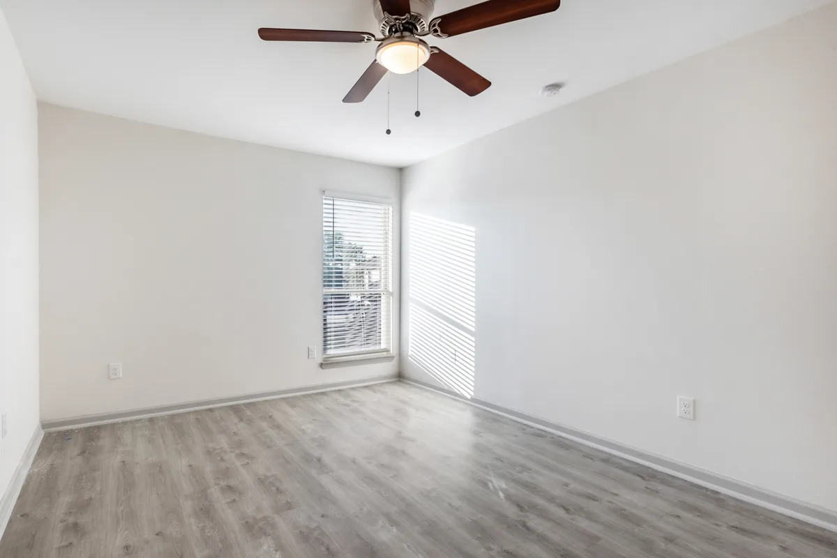 Bedroom with a ceiling fan, wood-look flooring, and a window with blinds