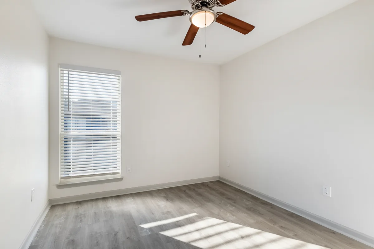 Bedroom with a ceiling fan, light wood-look flooring, and natural light through the window blinds