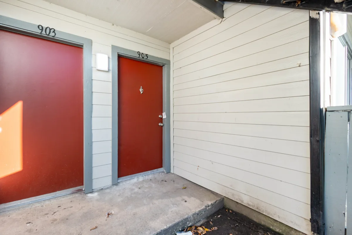 Exterior entrance with two red doors and a small covered porch