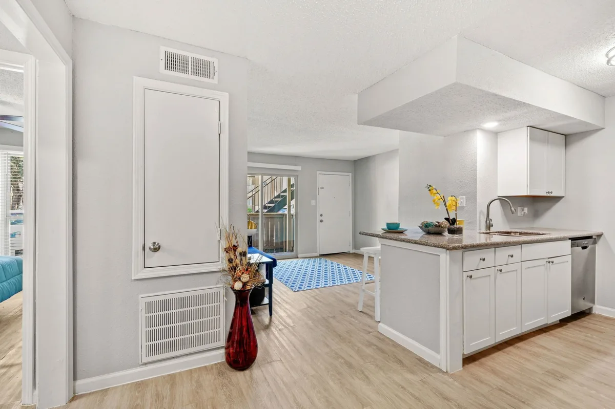 Kitchen peninsula with granite-look counters, white cabinets, and a stainless dishwasher