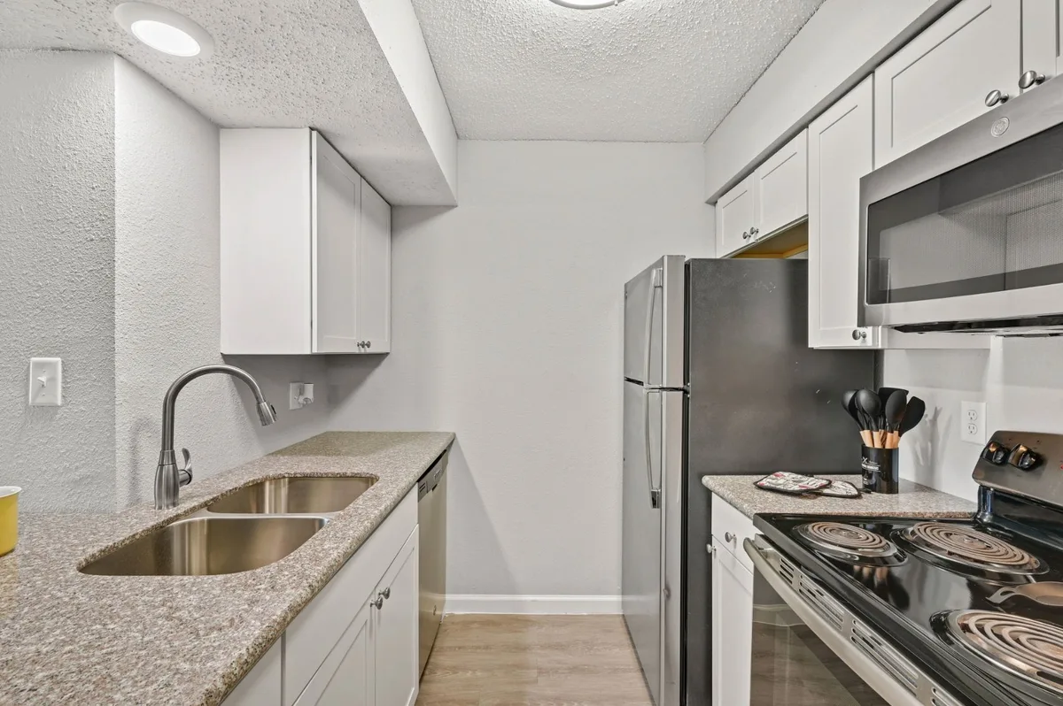 Renovated kitchen with white shaker cabinets, granite-look counters, and stainless-steel appliances