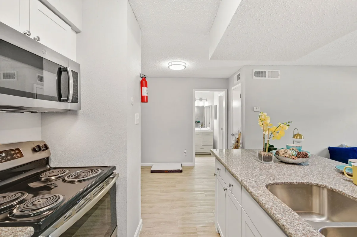 Galley kitchen with a stainless range and microwave opening to a hallway and bathroom