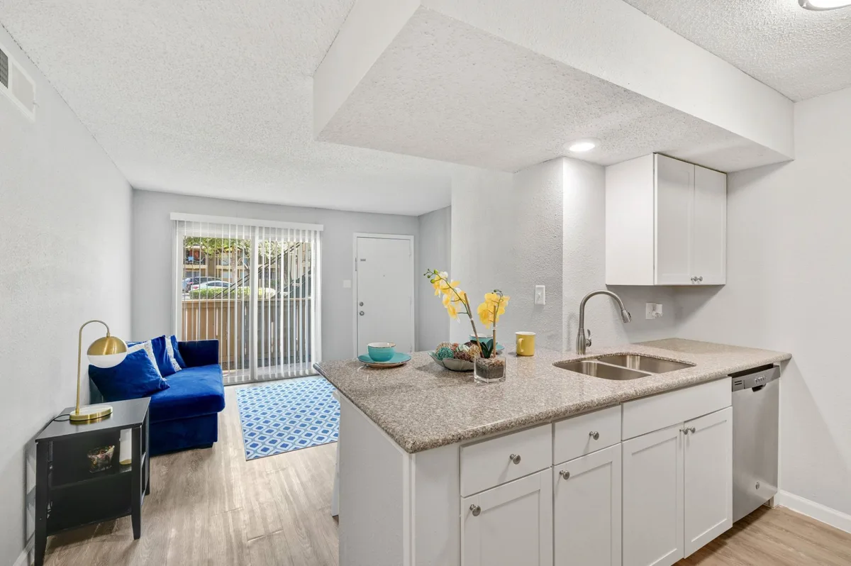 Open living area with a white pantry cabinet, granite breakfast bar, and patio-door light