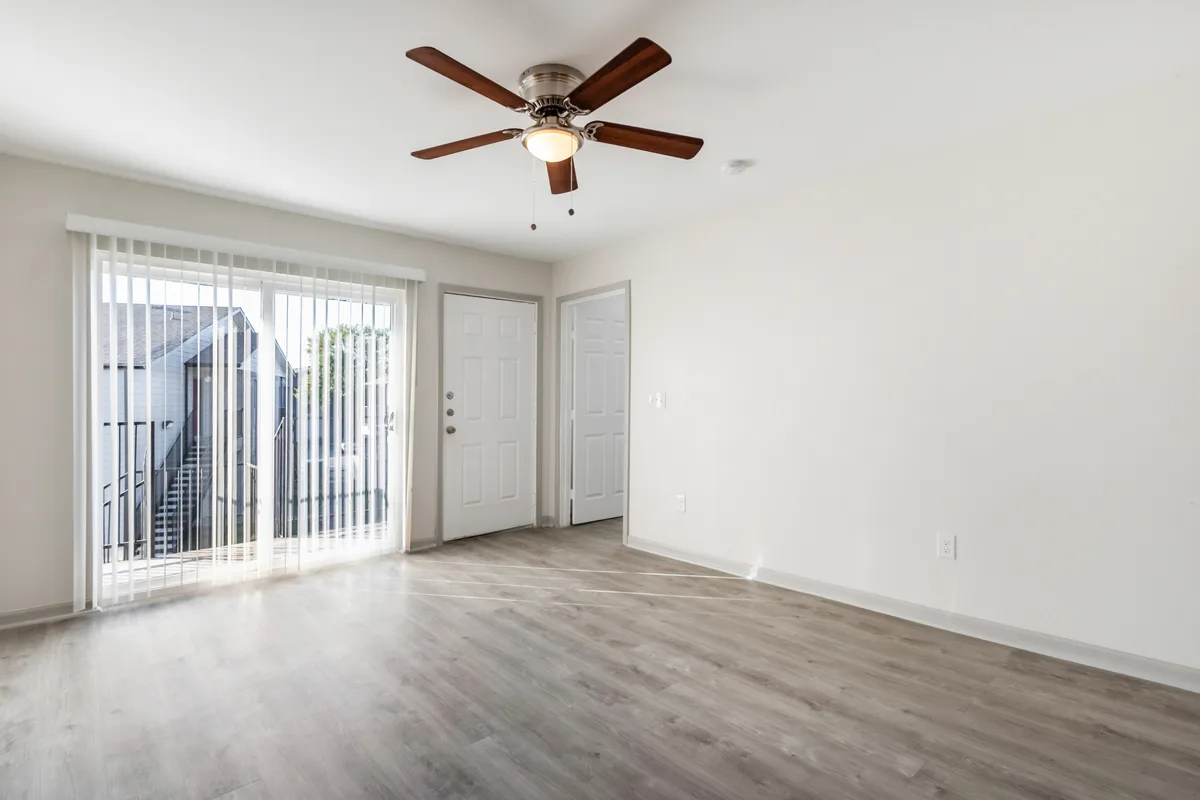 Bright living room with a ceiling fan, sliding glass doors to a patio, and wood-look plank flooring