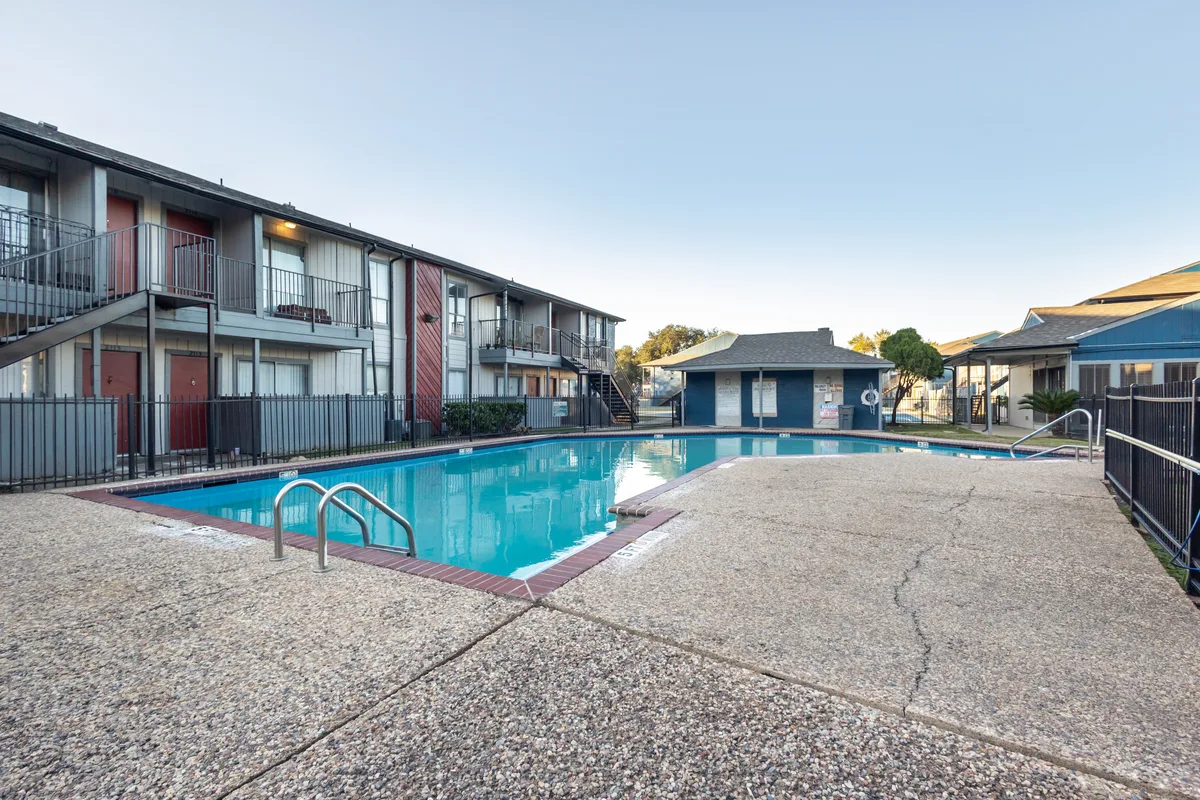 Swimming pool surrounded by apartment buildings, with clear blue water and a concrete deck